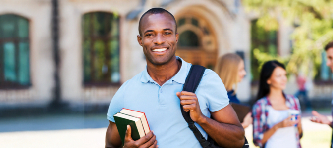 A smiling African American male college student with a backpack and books.