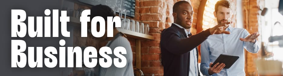 Two business professionals reviewing plans together inside a modern cafe setting. To the left, the words: built for business.