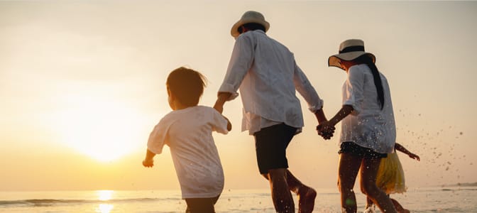 A family holding hands running into the ocean.